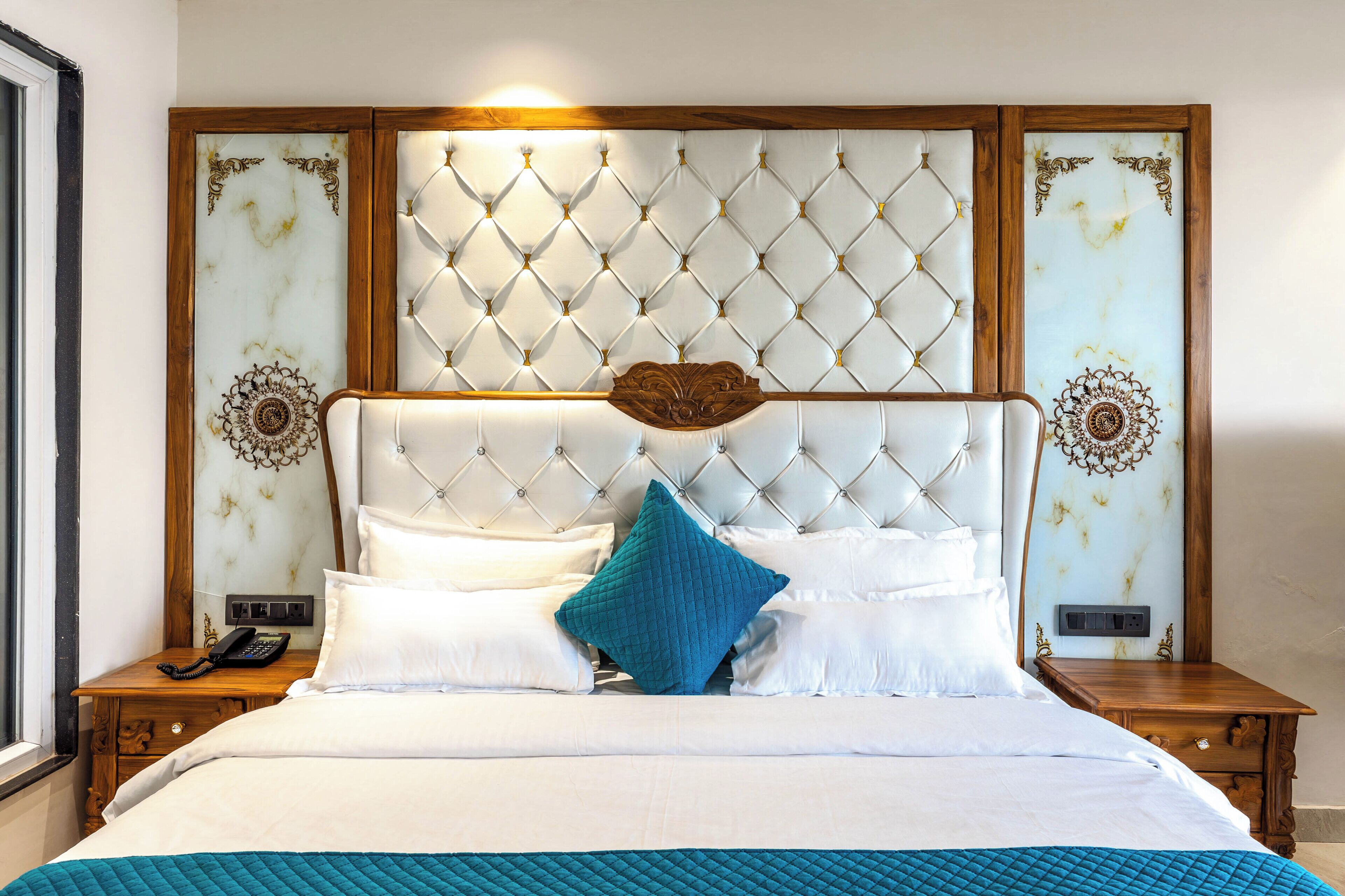 Une chambre d’hôtel avec un grand lit, une tête de lit en bois et un panneau décoratif mural.