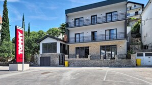 En moderne bygning i to etager med en stenfasadde, store vinduer og en balkon.