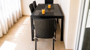 Un coin repas avec une table et des chaises, un verre de jus d’orange et une vue sur l’extérieur.