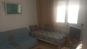 A room with a bed, a sofa, a small table, and a radiator.