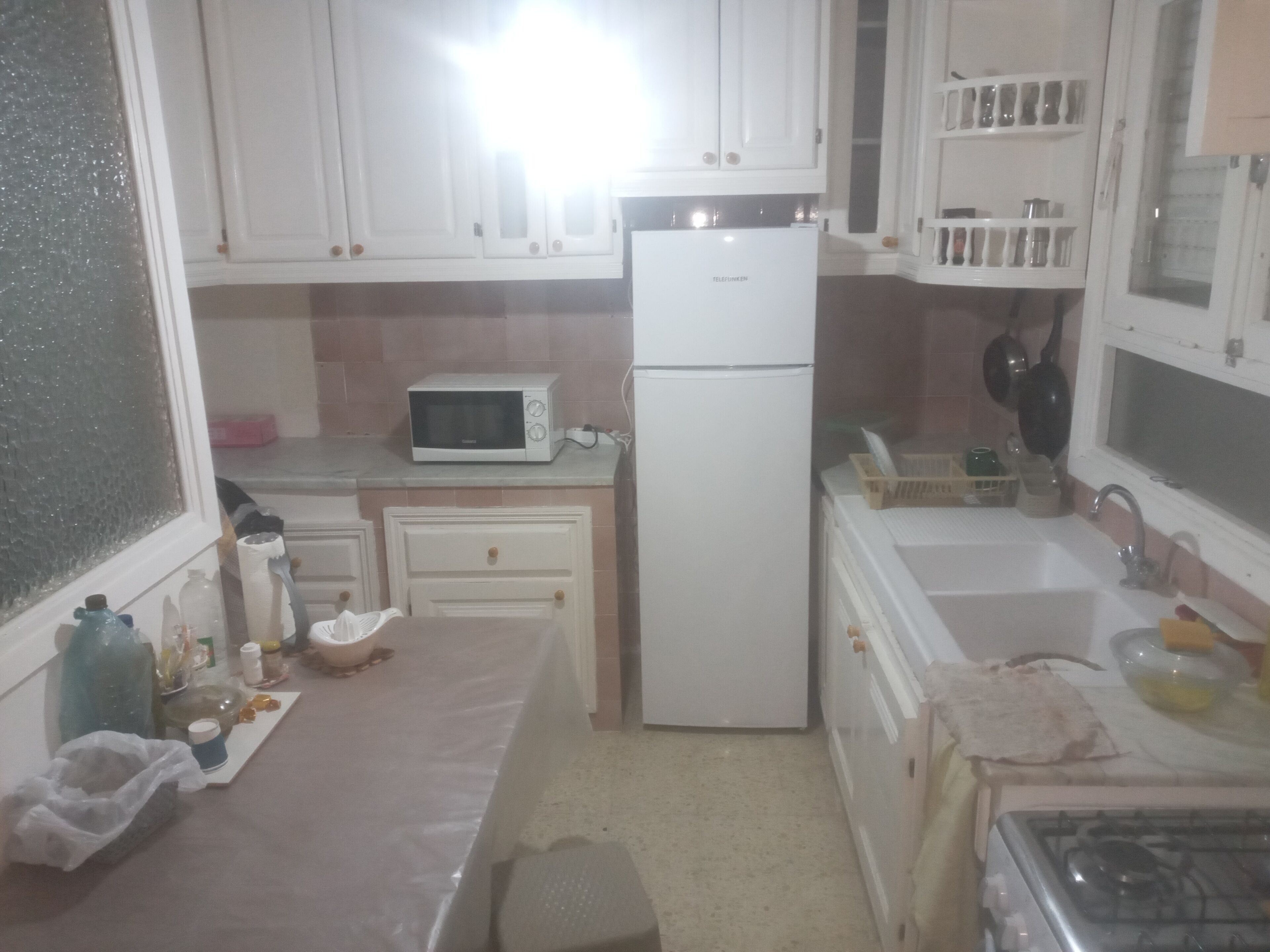 A compact kitchen with white cabinets, a microwave, a refrigerator, a sink, and a stove.