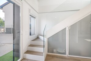 A staircase with glass railings and a door leading to an outdoor area.