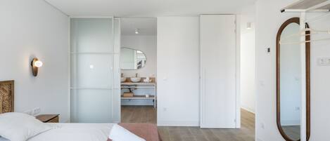 Ein modernes Schlafzimmer mit Bett, Nachttisch, großem Spiegel und Deckenventilator.