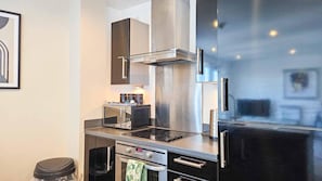 Uma cozinha moderna com exaustor de aço inoxidável, forno embutido, micro-ondas e geladeira preta.