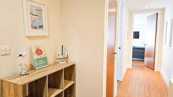A hallway with a wooden console table, a framed picture, a small ship model, and a 'You're a Superhost!' sign.