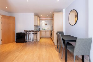 Una cocina moderna con armarios de madera, un comedor con mesa y sillas, y un espejo en la pared.
