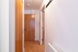 Ein Korridor mit Holztüren, einem weißen Heizkörper und einem Lichtschalter an der Wand.