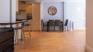 Une cuisine moderne avec des meubles en bois, un coin repas agrémenté d’un miroir rond et un radiateur.