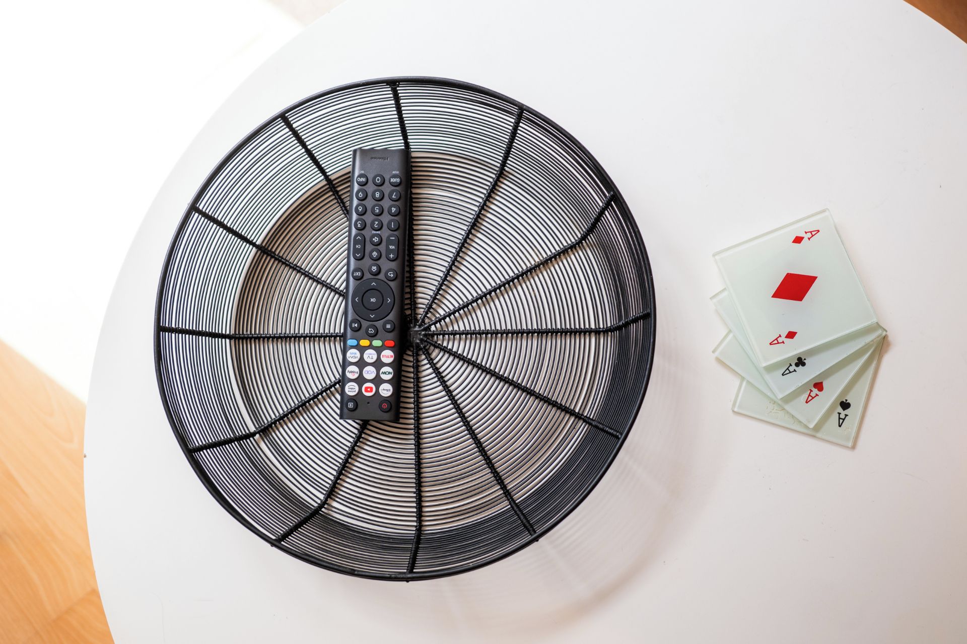 A circular fan with a remote control and playing cards on a white surface.