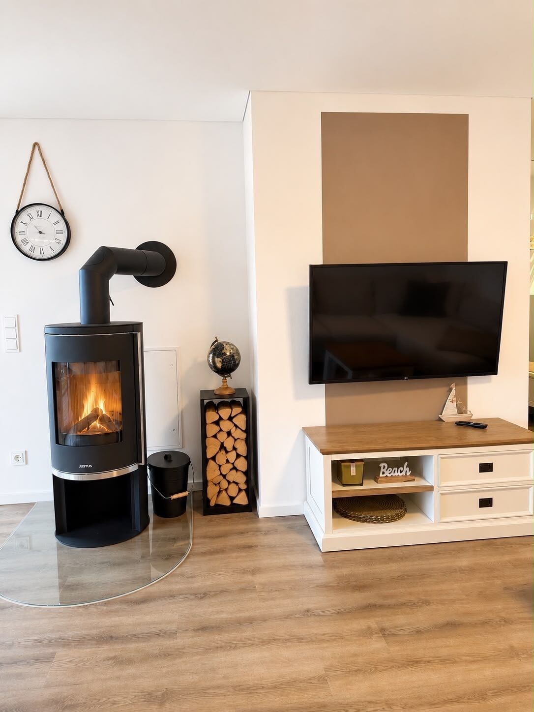 A modern living room with a wood-burning stove, a flat-screen TV, and a minimalist design.