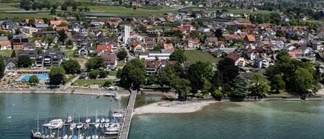 An aerial view of a coastal town with a marina, residential buildings, and a prominent church.