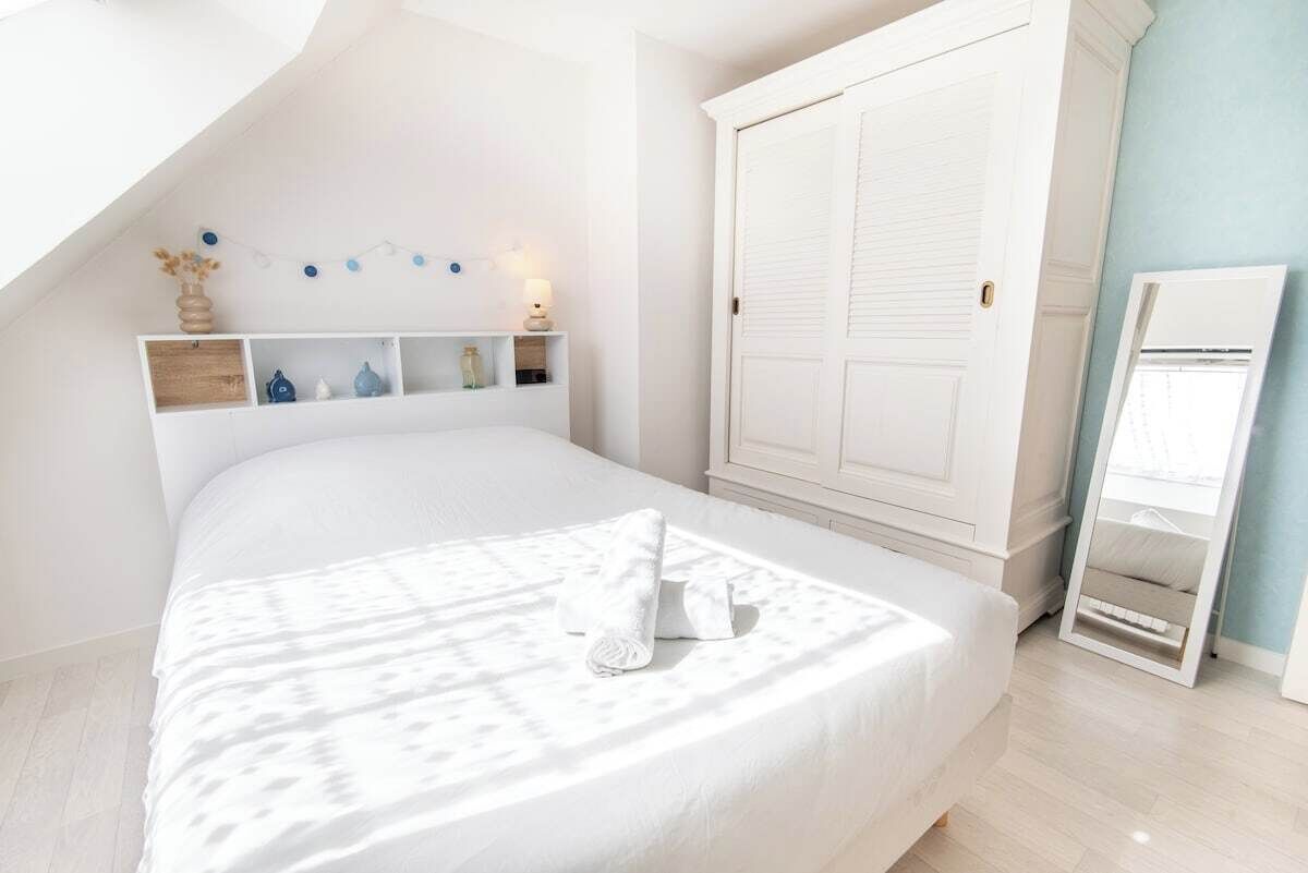 Une chambre à coucher comprenant un lit, une armoire, un miroir et une étagère avec des objets décoratifs.