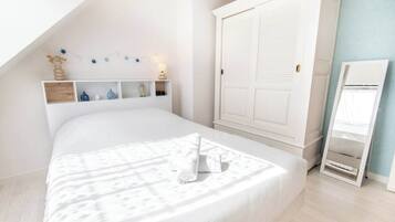 Une chambre à coucher comprenant un lit, une armoire, un miroir et une étagère avec des objets décoratifs.