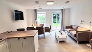 Ein modernes Wohnzimmer mit Sofa, Couchtisch und Essbereich.