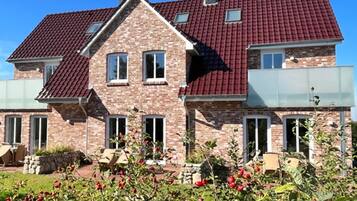 Ein zweistöckiges Haus mit rotem Ziegeldach, Backsteinwänden und einem Garten mit roten Beeren.