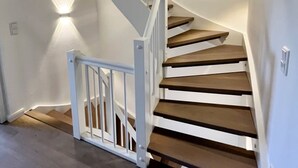 Eine Wendeltreppe mit weißen Geländern und Holzstufen, die zu einer oberen Etage führt.