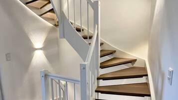 Eine Wendeltreppe mit weißen Geländern und Holzstufen, die zu einer oberen Etage führt.