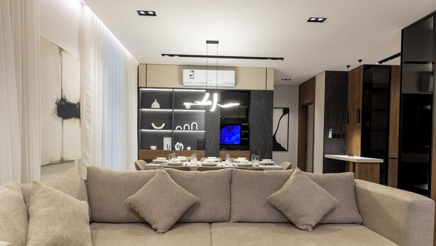 Una sala de estar moderna con un sofá, un comedor con mesa puesta y un televisor.