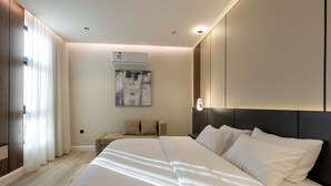 Una habitación de hotel moderna con una cama grande, una mesita de noche, un sofá y un equipo de aire acondicionado.