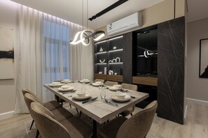 Une salle à manger moderne avec une table en marbre, des chaises rembourrées et un luminaire suspendu contemporain.
