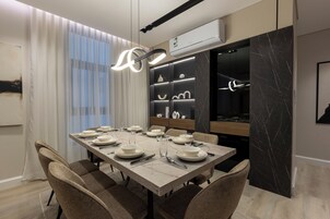Un comedor moderno con una mesa de mármol, sillas acolchadas y una lámpara colgante contemporánea.