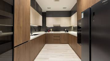 Une cuisine moderne avec des meubles en bois, un réfrigérateur noir et un plan de travail de couleur claire.