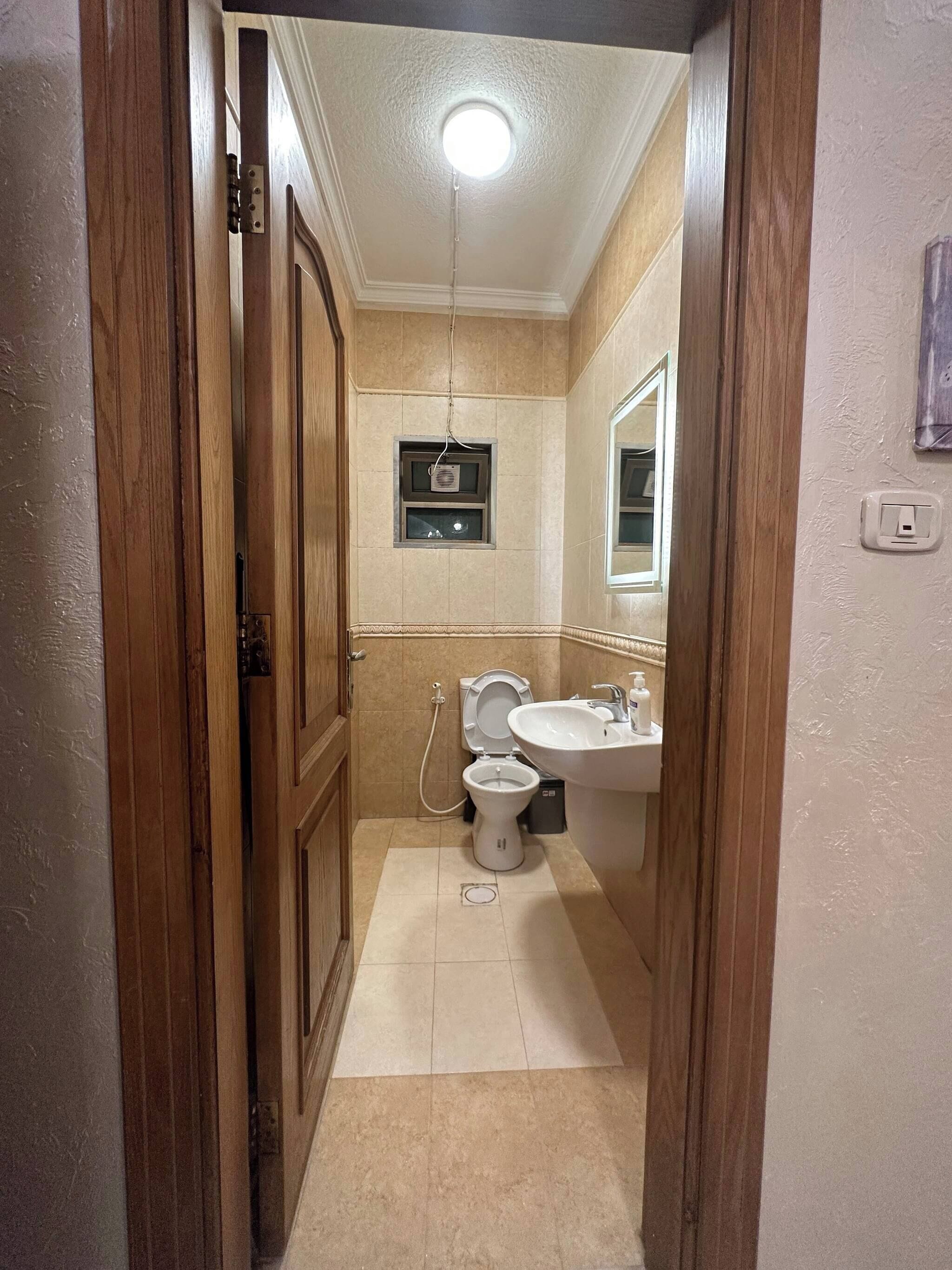 A bathroom with a toilet, sink, and mirror.
