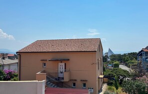 A multi-story building with a tiled roof, a visible staircase, and a small balcony. - Nice apartment in Rijeka with house sea view (Rijeka)