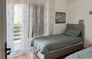 A bedroom with a bed, a window with sheer curtains, a framed picture on the wall, and a welcome pillow. - Nice apartment in Rijeka with house sea view (Rijeka)