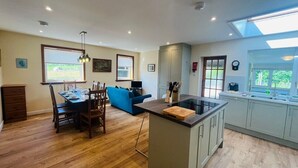 A spacious living area with a dining table, blue sofa, and a kitchen with a large island. - Coire Breac near Roy Bridge (Inverroy)