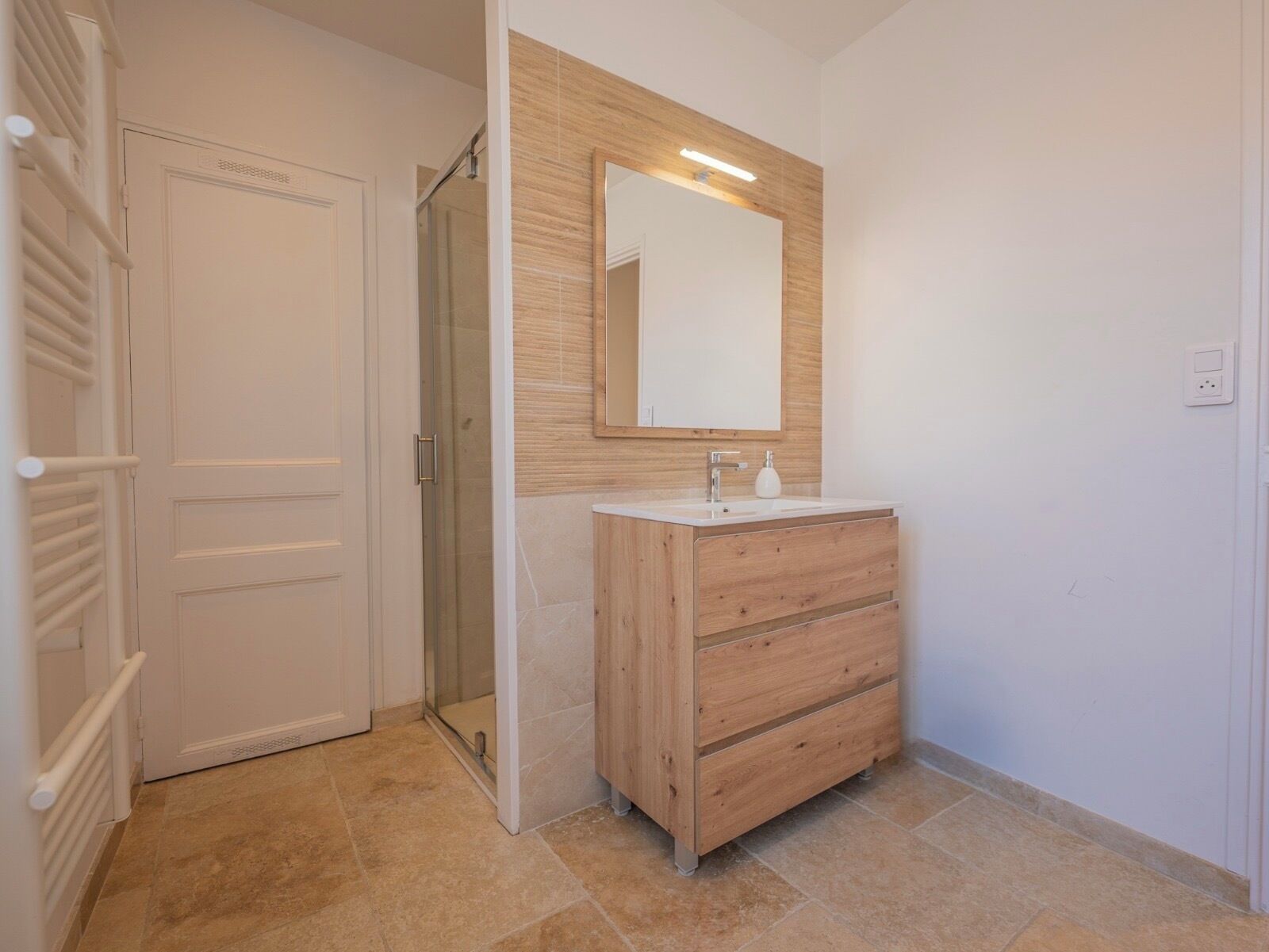 A bathroom with a wooden vanity, a mirror, and a shower.