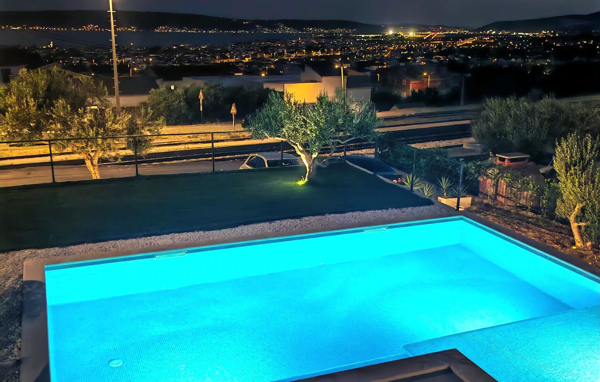 A swimming pool with a view of a cityscape at night.