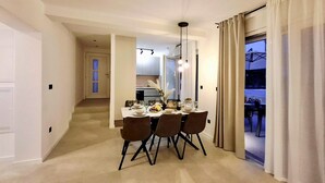 A dining area with a table set for four, a kitchen in the background, and a view through a glass door. - Gorgeous home in Kastel Stari (Kastel Stari)