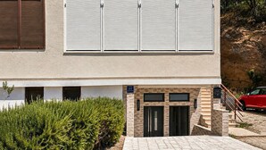 Un bâtiment moderne à la façade plate, avec une entrée principale dotée d’une porte et un petit escalier menant à l’entrée.