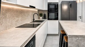Une cuisine moderne équipée d’un lave-vaisselle encastré, d’un évier, d’un four à micro-ondes et d’un réfrigérateur.