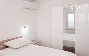 A bedroom with a bed, a bedside table, a mirror, and an air conditioning unit. - Nice apartment in Makarska with WiFi (Makarska)