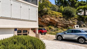 Un edificio moderno con facciata in pietra, un'auto rossa parcheggiata davanti e un'auto argentata nel vialetto.