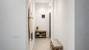 A hallway with a bench, a shoe rack, and a surfboard leaning against the wall. - Lovely apartment in Mimice with WiFi (Mimice)