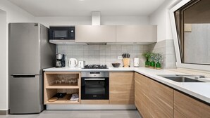 Una cucina moderna con un forno a microonde Bosch, un forno integrato, una macchina da caffè e una dispensa per il vino.