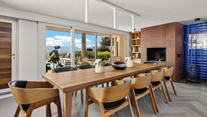 Un'area pranzo moderna con tavolo e sedie in legno, un camino e vista sull'esterno.