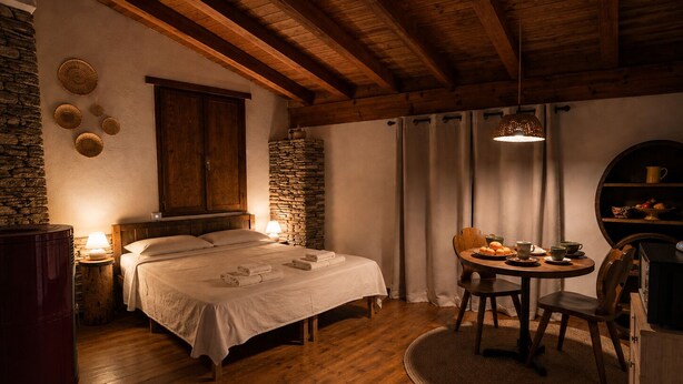 Una habitación acogedora con una cama, una mesa redonda con sillas, un muro de piedra y un techo de madera.