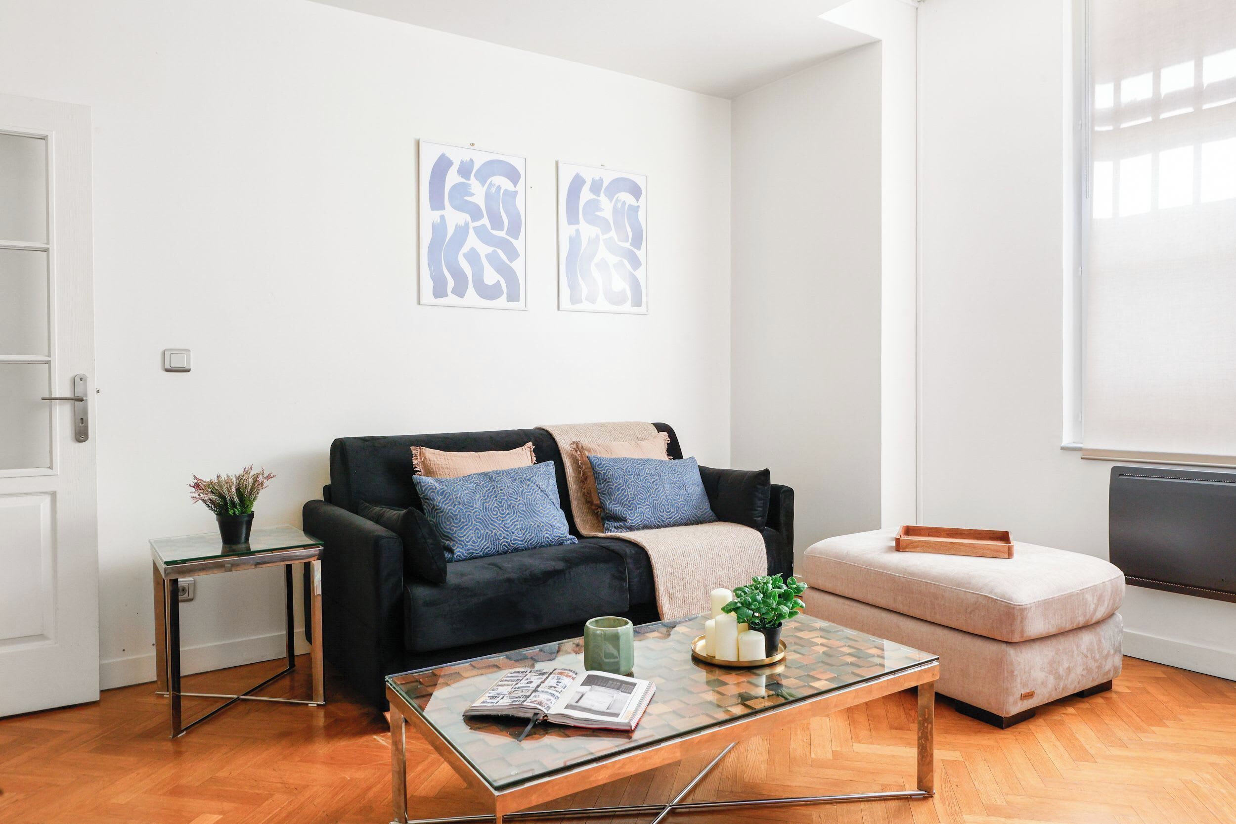 A modern living room with a sofa, ottoman, coffee table, and wall art.