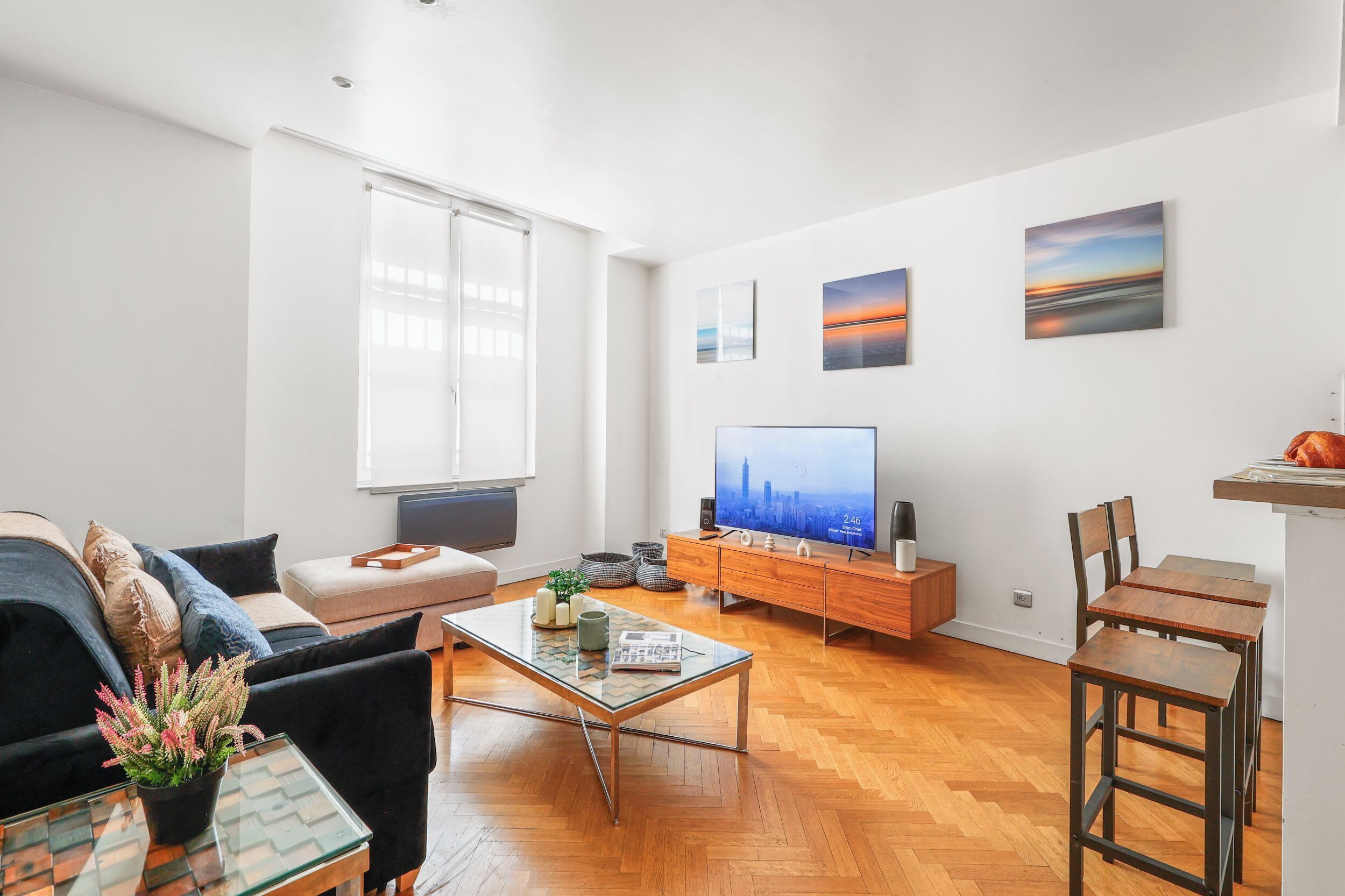 Een moderne woonkamer met een bank, salontafel, televisie en kunst aan de muur.