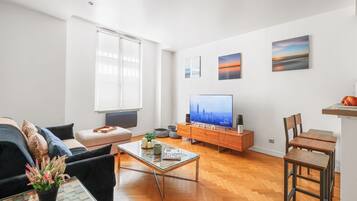 Een moderne woonkamer met een bank, salontafel, televisie en kunst aan de muur.