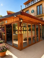 Un edificio de madera con grandes puertas de cristal y un letrero que dice 'AGVA SECRET GARDEN'.