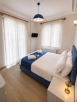 Una habitación de hotel con cama, televisor, mesita de noche y lámpara.