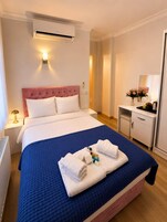 Una habitación de hotel con cama, mesita de noche, escritorio, espejo y aire acondicionado.