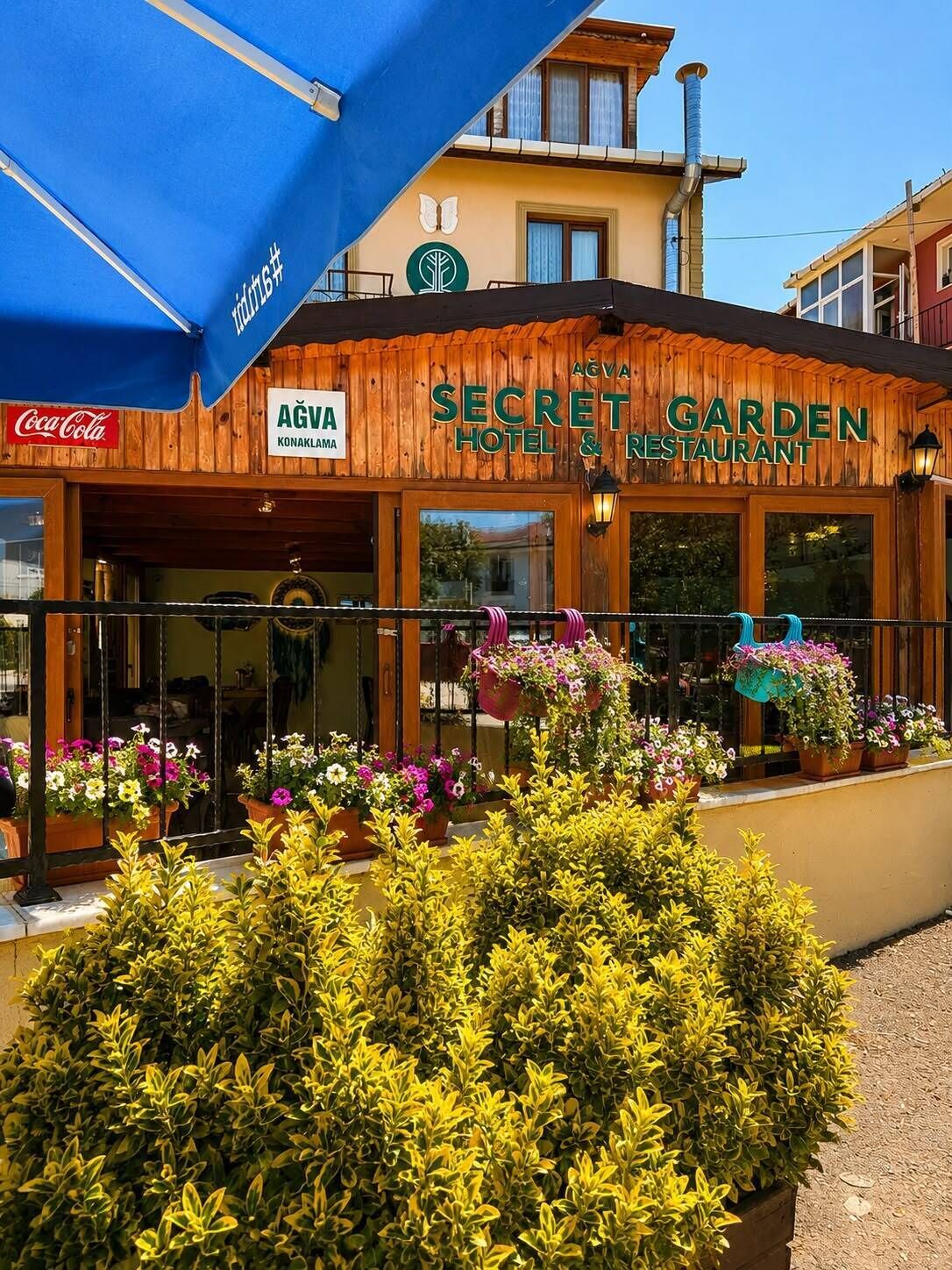 A wooden building with a sign reading 'Secret Garden Hotel & Restaurant.'