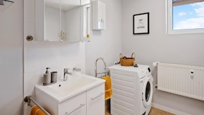 A bathroom with a sink, mirror, towel rack, and a washing machine. - Harzträume Apartments Wernigerode (Wernigerode)