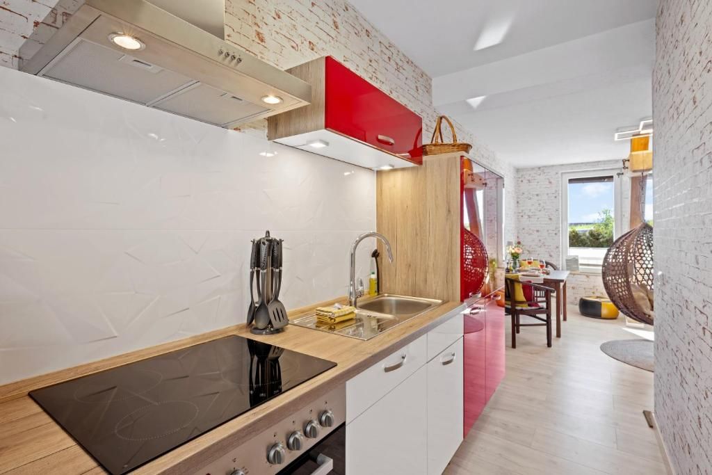 Cozinha moderna com fogão embutido, pia e armário vermelho.